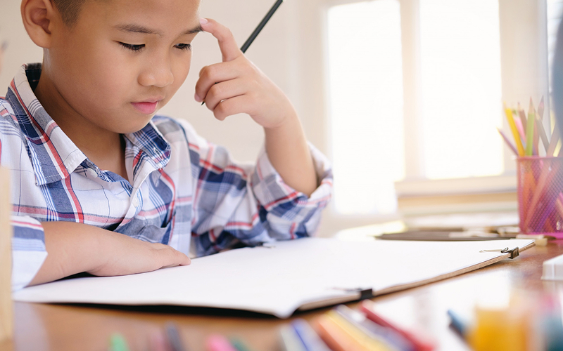Young student practicing Chinese writing and stroke order techniques.