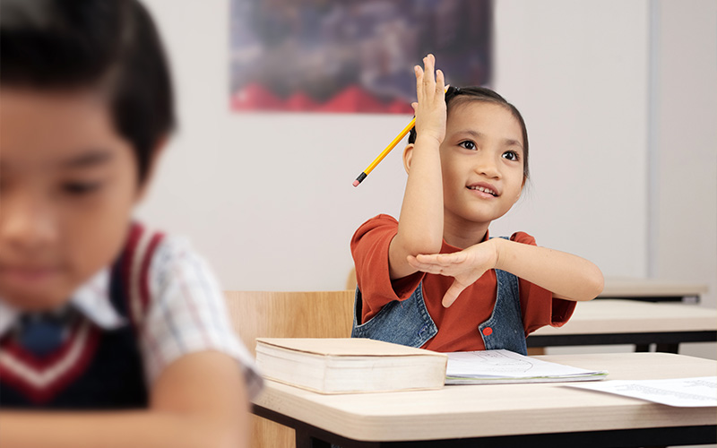 A student confidently raising her hand