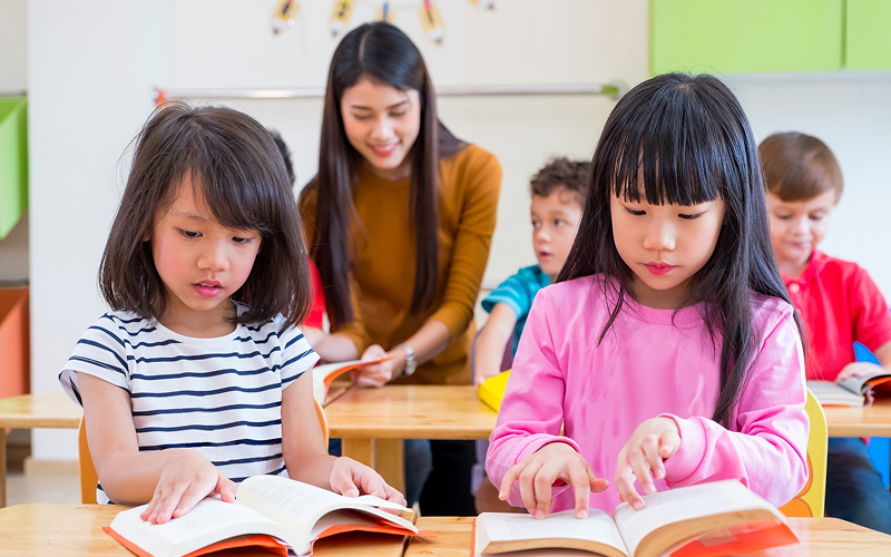 Students reading books during a story-based Chinese learning session.