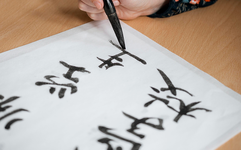 Hand practicing traditional calligraphy to understand Chinese character types.
