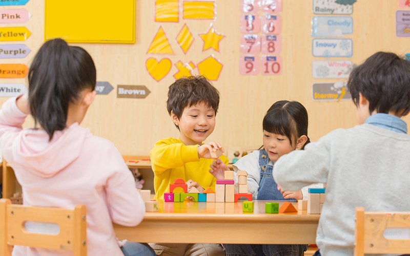 Children playing with blocks for interactive game-based language learning.